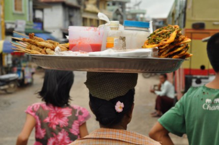 In Burma people enjoy carrying things on the head. This woman sports a tray of snacks